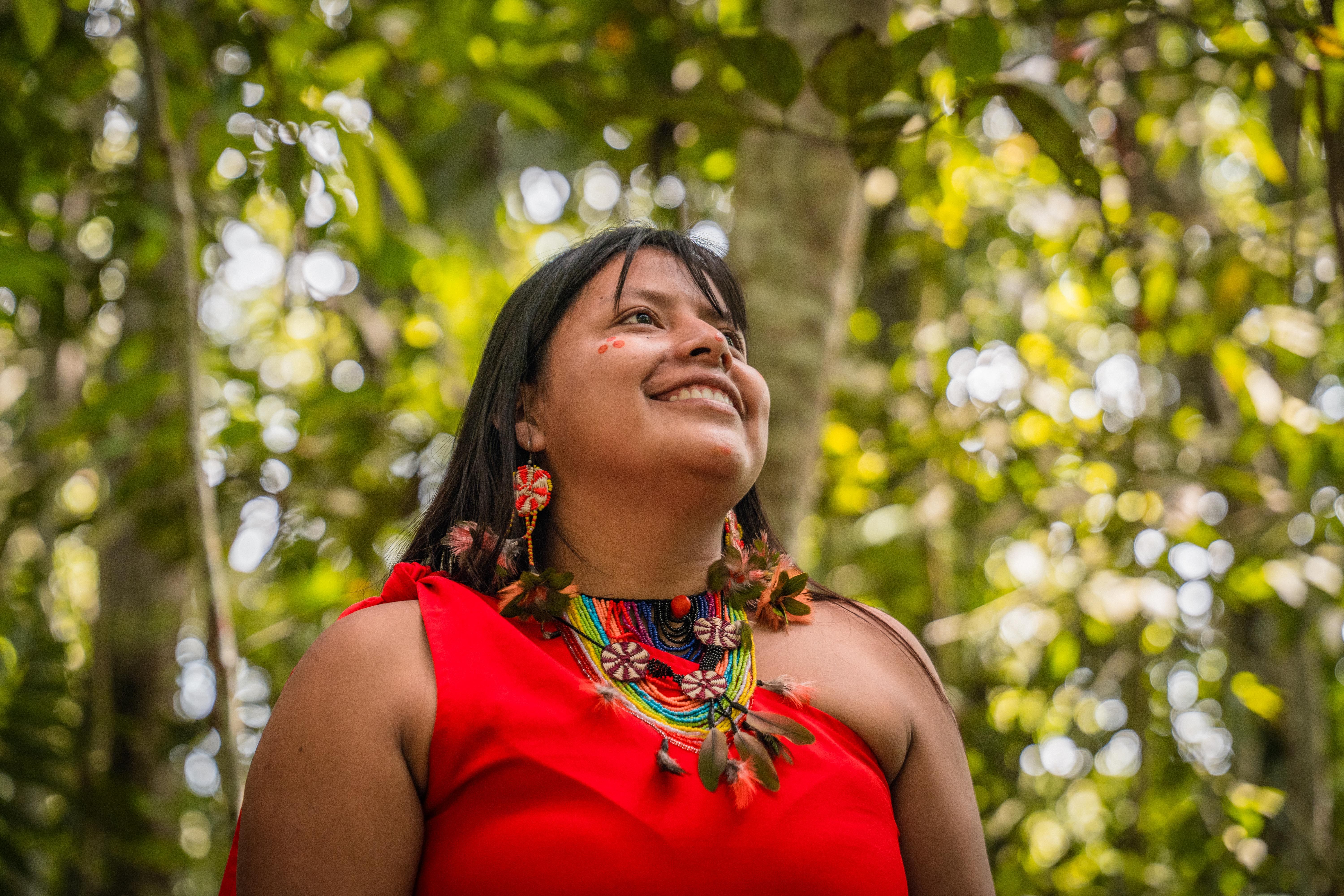 Mulher indígena sorrindo sob a copa da floresta amazônica